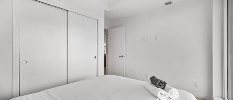A bedroom with a bed, a window, and a door.