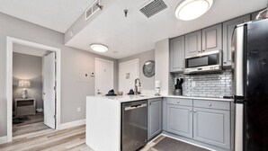 A modern kitchen with grey cabinets, stainless steel appliances, and a central island. - Studio Near Universal Lake View Pool & Gym (Orlando)