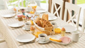 A breakfast table set with plates, cups, a basket of bread, eggs, and orange juice. - Delmaro, vacation home 6 pers., near beach. (Middelkerke)