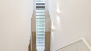 A staircase with a handrail, a window with blinds, and a light fixture on the wall. - Delmaro, vacation home 6 pers., near beach. (Middelkerke)