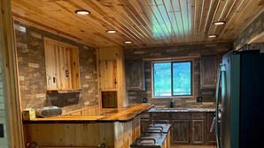 A rustic kitchen with wooden cabinets, a central island, and a large window. - Gorgeous house for rent during Sturgis Rally 2026 (Rapid City)