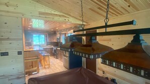 A wooden interior with a dining area, kitchen, and a hanging light fixture. - Gorgeous house for rent during Sturgis Rally 2026 (Rapid City)