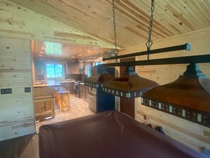 Ein Holzkaminzimmer mit Essbereich, Küche und einer Hängeleuchte.