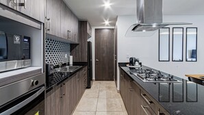 Une cuisine moderne dotée d’appareils électroménagers en acier inoxydable, de meubles en bois et d’un dosseret carrelé.