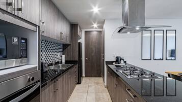 A modern kitchen with stainless steel appliances, wooden cabinets, and a tiled backsplash.