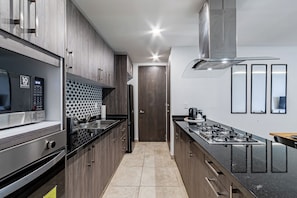 A modern kitchen with stainless steel appliances, wooden cabinets, and a tiled backsplash. - Black & White Apartment, an oasis in Cuernavaca (Cuernavaca)