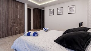 Une chambre à coucher moderne, avec un lit, une armoire et trois tableaux encadrés accrochés au mur.
