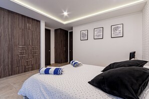 A modern bedroom with a bed, a wardrobe, and three framed pictures on the wall. - Black & White Apartment, an oasis in Cuernavaca (Cuernavaca)