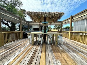 A wooden deck with a thatched roof bar area, white chairs, and a sign reading 'HIDDEN OASIS.' - Cozy 1-bedroom bunkhouse in beautiful Port O'Connor with plenty of room to sleep (Port O'Connor)