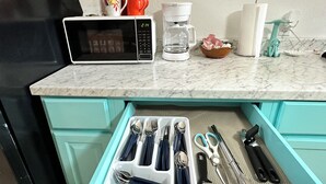 Una cucina con forno a microonde, macchina del caffè e cassetto per utensili.