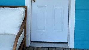 Una porta bianca con una serratura e una piccola finestra, incassata in un muro color azzurro-verde.