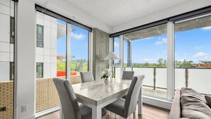 Ein moderner Essbereich mit Tisch und Stühlen, großen Fenstern und einem Balkon mit Blick.