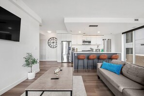 Una sala de estar moderna con un sofá, una mesa de centro y un televisor montado en la pared.