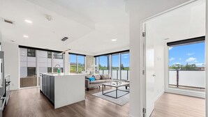 Eine geräumige Wohnung mit Küche, Wohnbereich und großen Fenstern mit Blick ins Freie.