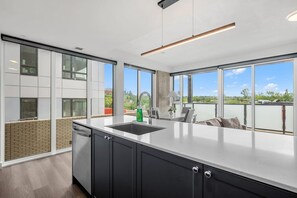 Una cocina moderna con un amplio ventanal, un lavamanos y una zona de comedor con sillas.