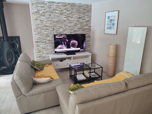 A living room with a television, two sofas, a coffee table, and a fireplace. - Vrbo Property (Lacanau)