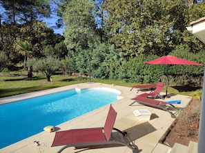 A swimming pool with lounge chairs and a red umbrella. - Vrbo Property (Lacanau)