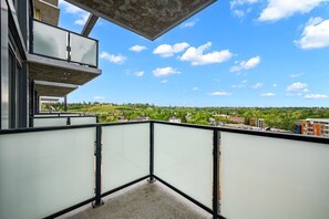 Ein Balkon mit freiem Blick auf eine grüne Landschaft und Gebäude in der Ferne.