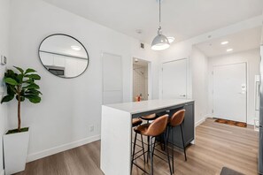 Eine moderne Küche mit einer zentralen Kochinsel, Barhocker, einem runden Spiegel und einem Blumentopf.