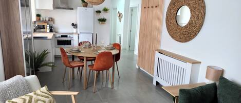 Una sala de estar moderna con un sofá verde, un sillón blanco y un comedor con una mesa redonda y sillas.
