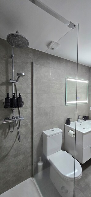 A modern bathroom with a shower, toilet, and sink. - Vrbo Property (Vilagarcía de Arousa)