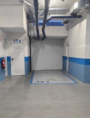 A parking garage with numbered parking spaces, a fire extinguisher, and a closed garage door.