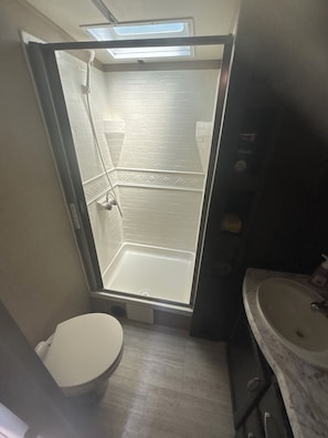 Et lille badeværelse med bruser, toilet og håndvask.