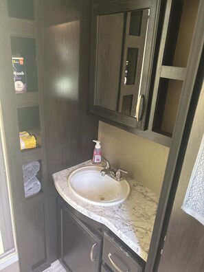 Ein Badezimmer mit Waschbecken, Spiegel und dunklen Holzsärchen.