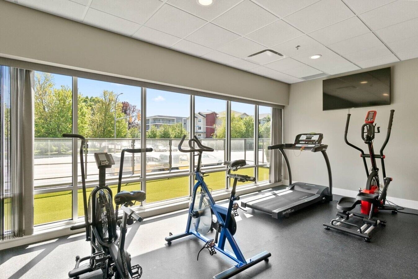 Une salle de sport équipée de vélos d’appartement, d’un tapis de course et d’un appareil de musculation elliptique.