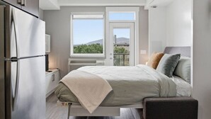 Une chambre à coucher comprenant un lit, une table de chevet, une fenêtre avec vue et un radiateur intégré.