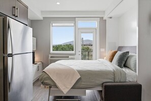 Ein Schlafzimmer mit Bett, Nachttisch, Fenster mit Blick und integrierter Heizung.