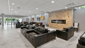 Un hall d’entrée spacieux, doté de canapés en cuir, d’un mur décoratif en pierre et d’une cheminée.