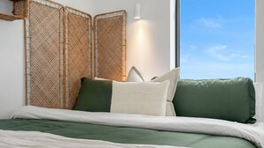 A bed with green bedding, a white throw blanket, and a view of the sky through a window. - NEW | Mins to Saddledome | Rooftop Patio | UG Park (Calgary)