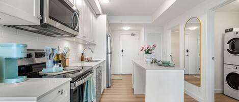 A modern kitchen with a microwave, stove, and coffee maker. There is a central island with a sink and a mirror.