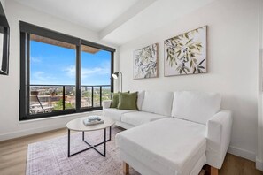 Ein modernes Wohnzimmer mit einem weißen Sofa, einem runden Couchtisch und zwei gerahmten Pflanzenbildern an der Wand.