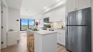 A modern kitchen with a central island, stainless steel appliances, and a view to the outside. - NEW | Mins to Saddledome | Rooftop Patio | UG Park (Calgary)