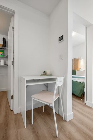 A white desk with a chair in a room with wooden flooring and white walls. - NEW | Mins to Saddledome | Rooftop Patio | UG Park (Calgary)