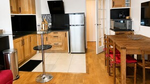 A compact kitchen with a refrigerator, microwave, and stove, wooden cabinets, and a dining area with a table and chairs.