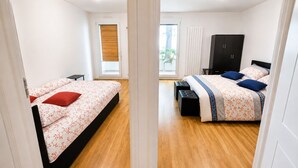 A bedroom with two beds, a wardrobe, and a sliding door leading to a balcony.