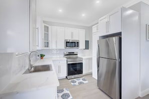 Una cocina moderna con armarios blancos, electrodomésticos de acero inoxidable y encimera de mármol.