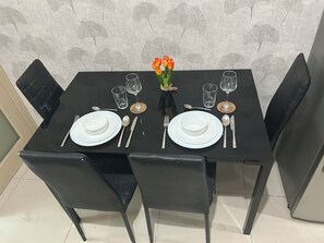 Una mesa de comedor dispuesta con platos, cubiertos y vasos, rodeada de sillas.