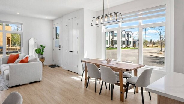 Ein modernes Wohnzimmer mit Essbereich, großen Fenstern und Blick auf eine Wohnstraße.
