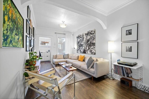 A modern living room with a sofa, coffee table, and bookshelves. - 2 Bed | Central | Min to Saddledome (Calgary)