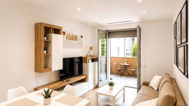 Ein modernes Wohnzimmer mit einem Flachbildfernseher, Holzbögen, einem Essbereich mit Tisch und Stühlen sowie einer Couch.