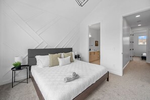 A modern bedroom with a large bed, bedside tables, and a view of the bathroom.
