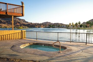 Ein Pool mit Holzboden und Metallgeländer, mit Blick auf einen Fluss und Berge im Hintergrund.