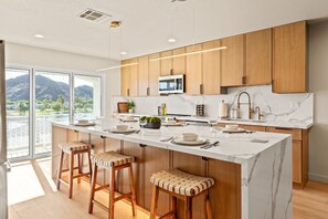 A modern kitchen with wooden cabinets, a marble island, and a large window overlooking a mountainous landscape. - Palm 1 - River Views, Private Dock & Boat Launch (Parker)