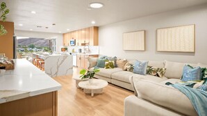 Uma sala de estar moderna com sofá, mesa de centro e área de cozinha com bancada e armários.