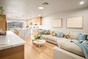 A modern living room with a sofa, coffee table, and a kitchen area with a counter and cabinets. - Palm 1 - River Views, Private Dock & Boat Launch (Parker)