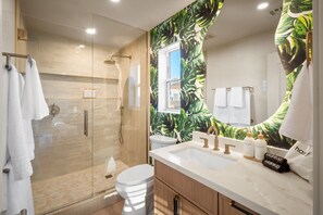 A modern bathroom with a glass shower enclosure, a white toilet, a vanity with a sink, and a large mirror. - Palm 1 - River Views, Private Dock & Boat Launch (Parker)